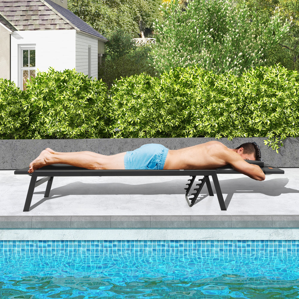 Adjustable black patio sunbathing lounge chair with a man lying face down, perfect for poolside relaxation.