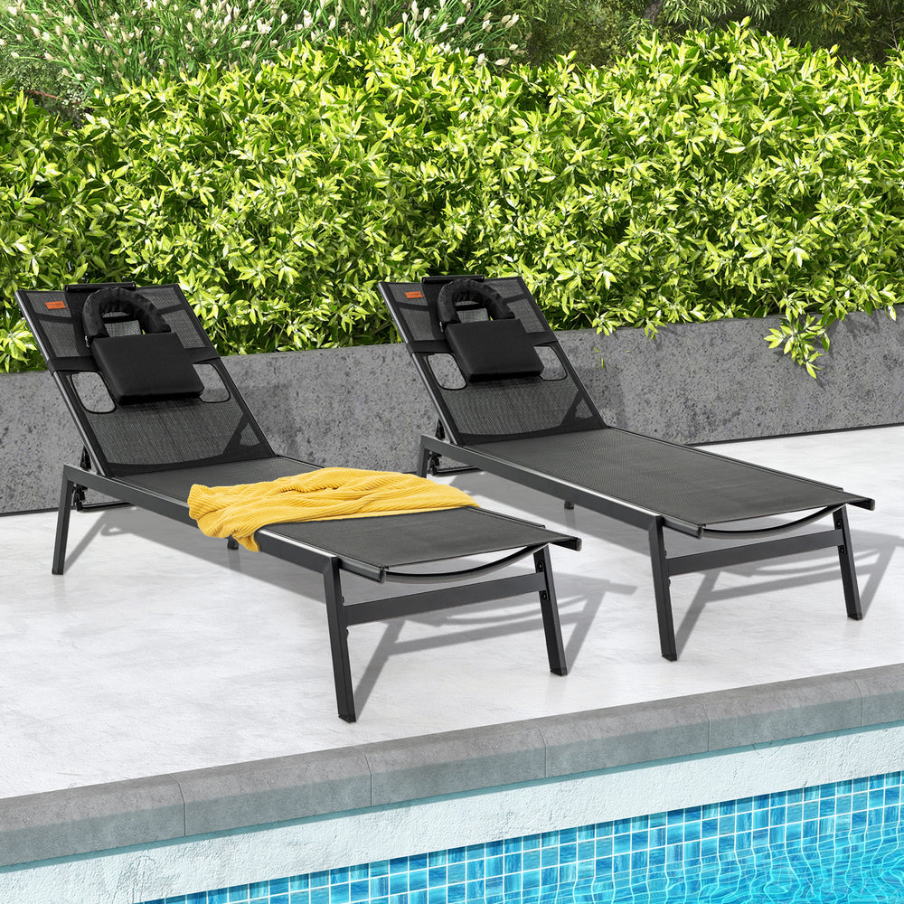 Two black patio sunbathing lounge chairs with adjustable backrests and pillows, ideal for poolside relaxation.