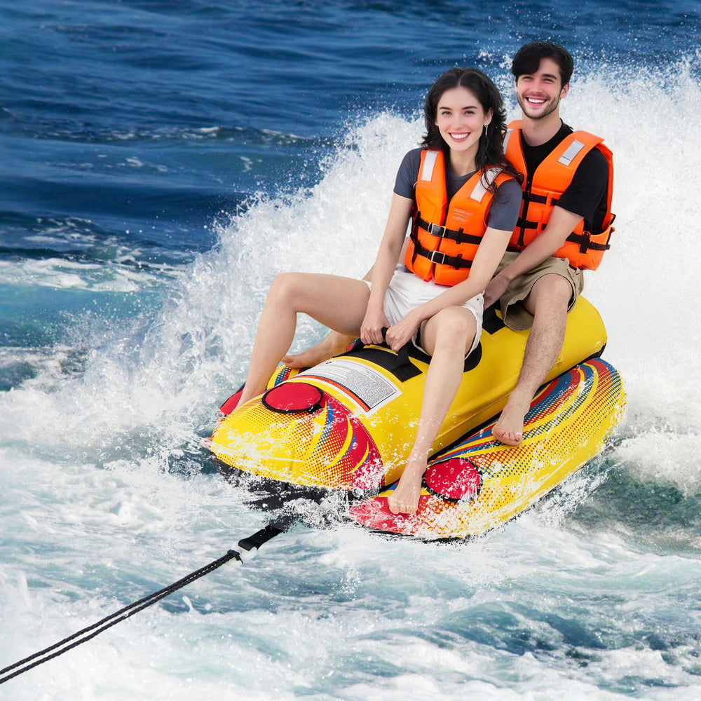 Two people enjoying a ride on a yellow inflatable towable tube, designed for boating and water sports activities.