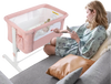 Portable pink baby bedside bassinet with adjustable height, breathable mesh, and travel bag for convenient use.