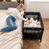 Portable baby playard in black with a soft mattress, perfect for infants and easy to fold for travel.