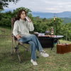 Portable camping chair with 400 lbs metal frame, featuring a cup holder, set in a scenic outdoor setting.