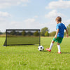 Child kicking a soccer ball towards a portable pop-up toddler soccer net with a heavy-duty metal frame on grass.