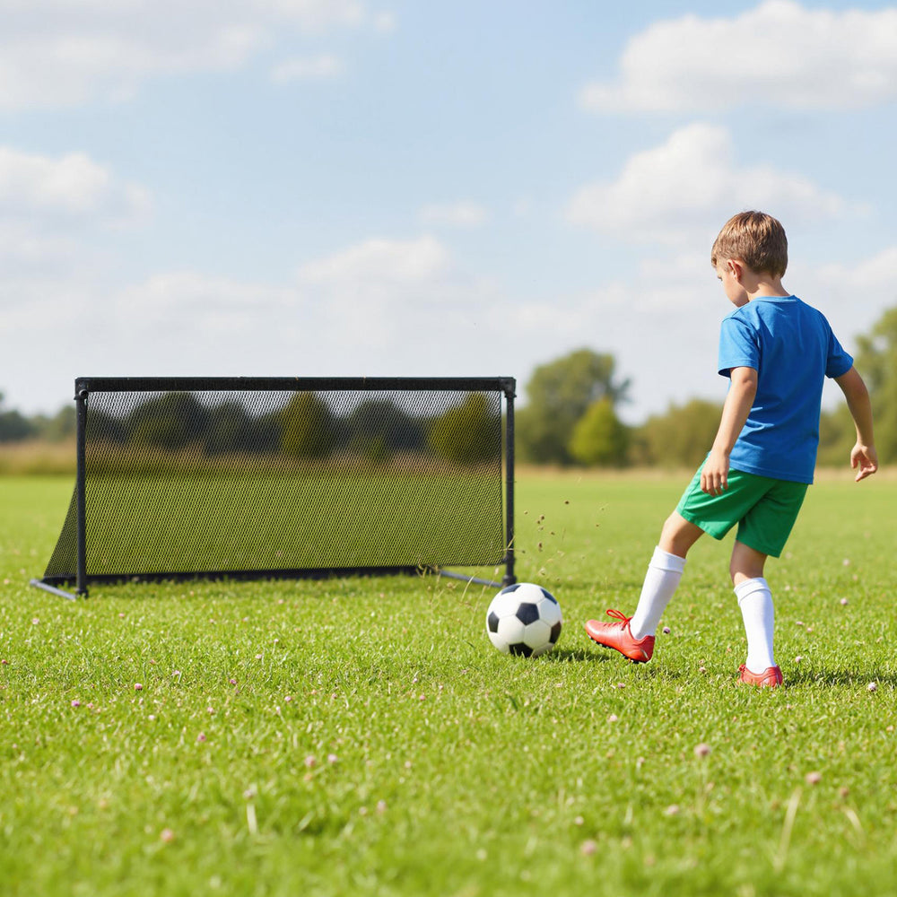 Child kicking a soccer ball towards a portable pop-up toddler soccer net with a heavy-duty metal frame on grass.