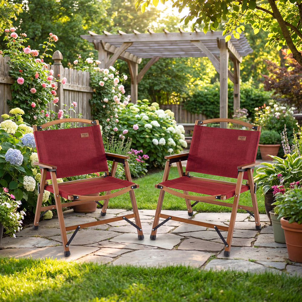 Two red portable folding camping chairs with bamboo frames in a garden setting, perfect for outdoor leisure and picnics.
