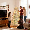 Pre-lit artificial Christmas tree with snow flocked branches, adorned with red berries, set up for festive decorating.