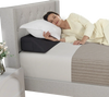 Bed wedge pillow in use, providing spinal support and filling gaps, with side storage pockets for essentials.