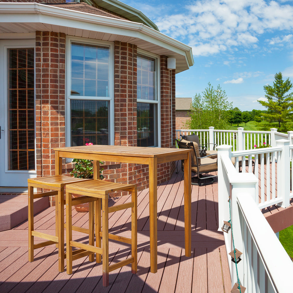 Rectangular acacia wood bar height table on a patio, perfect for dining and drinks in outdoor spaces.