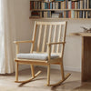 Natural solid rubber wood rocking chair with padded seat cushion, ideal for reading and relaxation in any home setting.