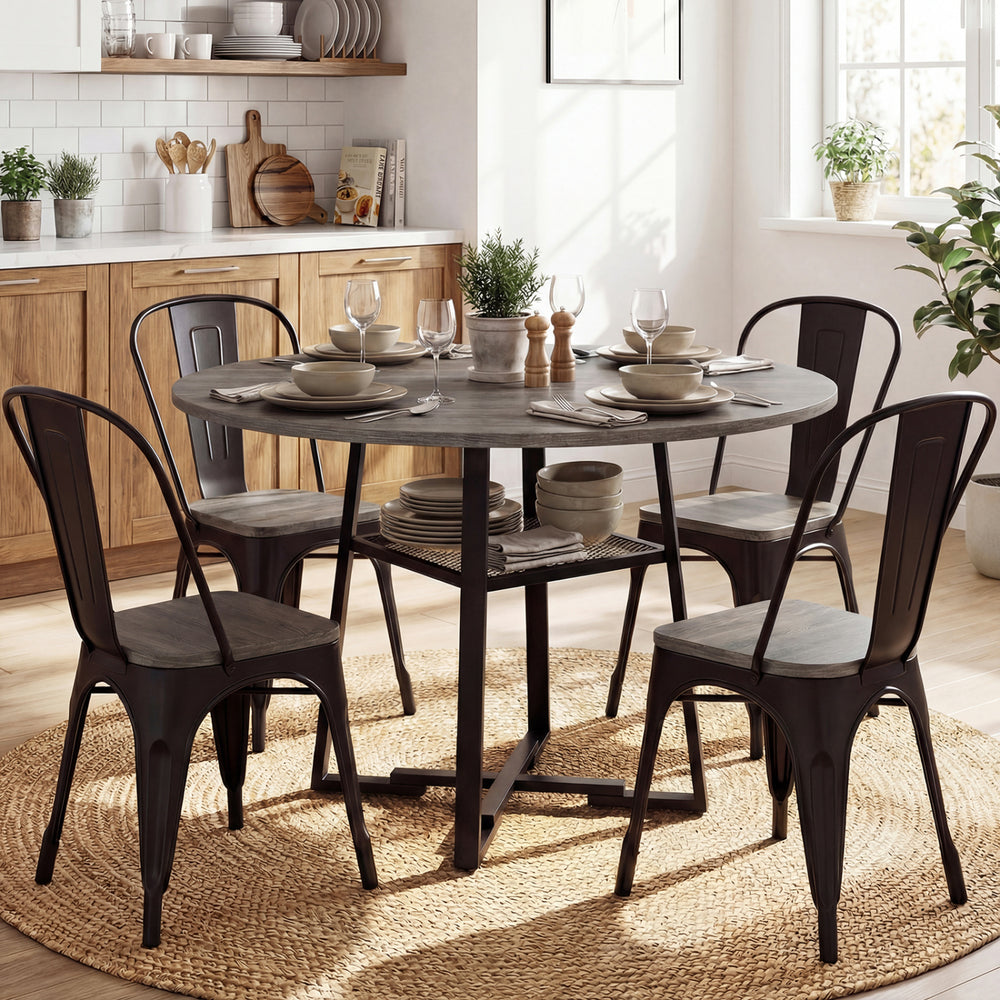 Round gray dining table for 4-6 with metal legs and storage shelf, styled with plates and glasses in a bright setting.