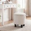 Round beige storage ottoman with removable lid, upholstered in linen fabric, ideal for use as a footrest or vanity.