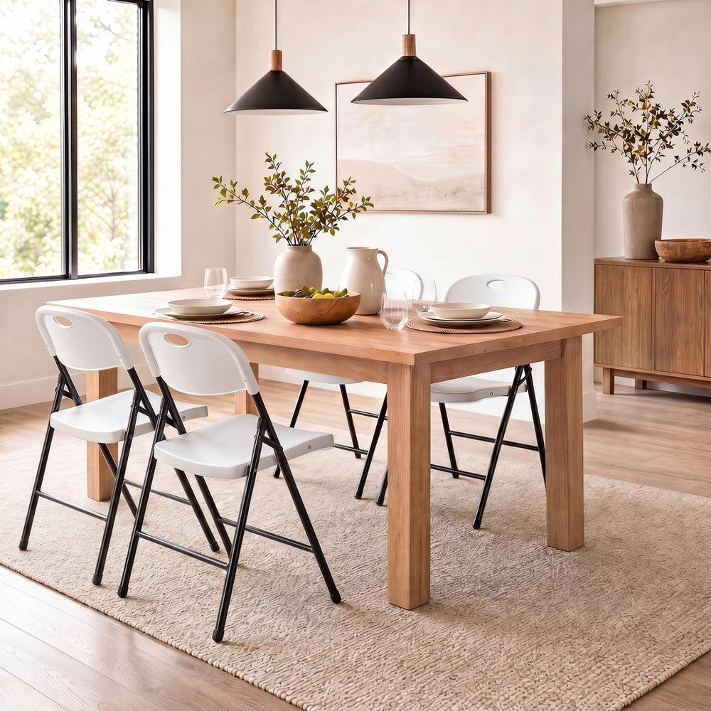 Set of four white foldable plastic chairs with ergonomic backrests, ideal for dining or events, featuring a sturdy design.