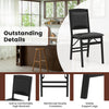 Black folding dining chair with padded seat and high backrest, featuring reinforced crossbars for stability and comfort.