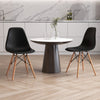 Two black armless dining chairs with wood legs around a round marble-top table, ideal for modern indoor spaces.