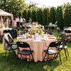 Black foldable plastic chairs with ergonomic backrests arranged around a dining table, ideal for events and gatherings.