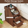 Side end table in walnut with charging station, open compartment, and two drawers for organized storage beside a sofa.