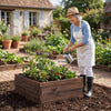 Square raised garden bed made of fir wood, ideal for growing flowers and vegetables, shown with a gardener watering.