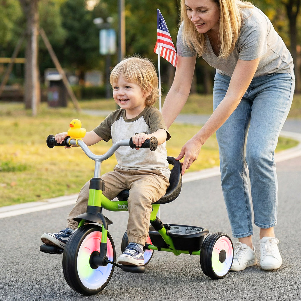 Toddler tricycle in green with glowing wheels, adjustable seat, and storage basket, perfect for outdoor adventures.