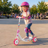 Toddler riding a pink kick scooter with LED light-up wheels and wide anti-slip deck in a park setting.