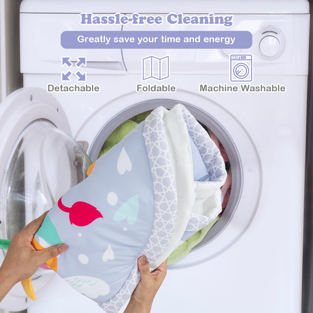 Baby play gym mat being placed in a washing machine, featuring a foldable, machine washable design for easy cleaning.