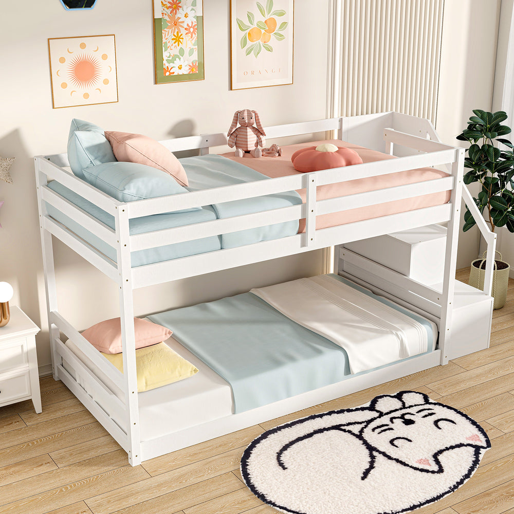 Twin over twin low bunk bed in white with storage stairs and safety guardrails, perfect for kids' rooms.