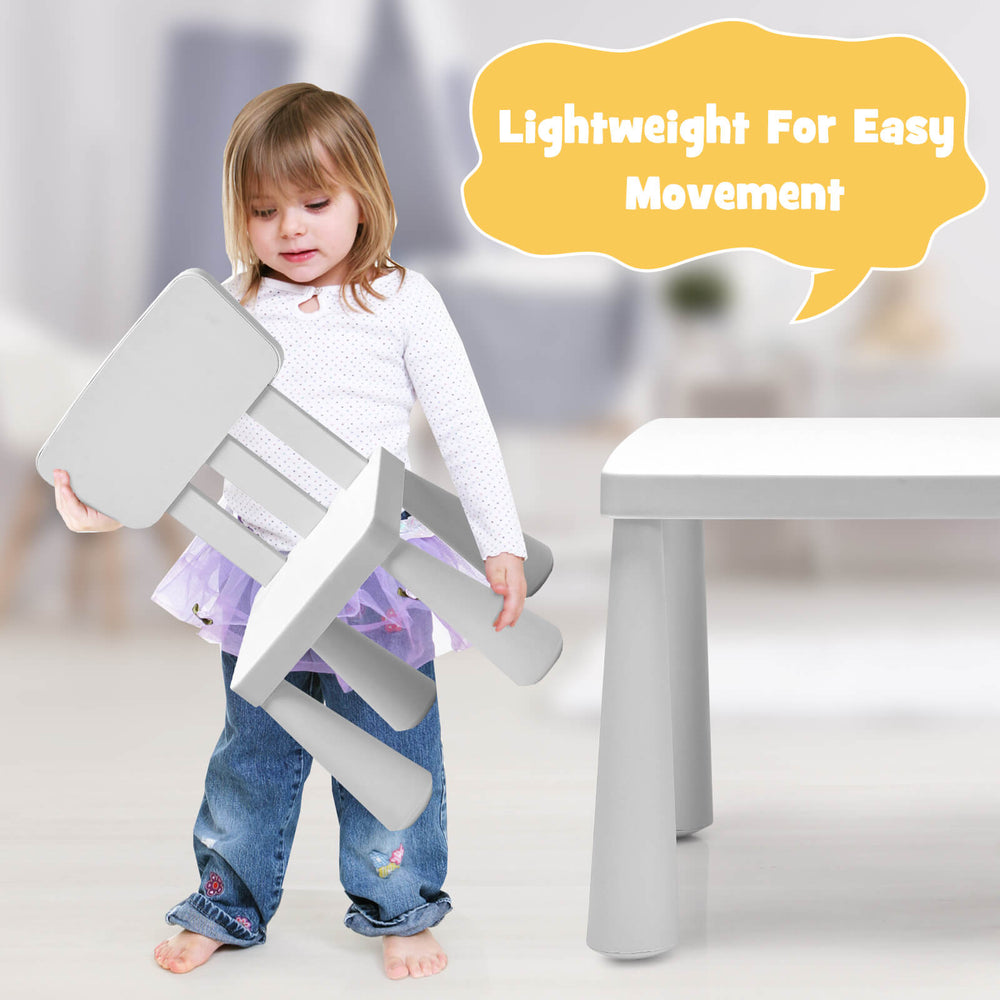 Toddler lifting a lightweight chair from the 3-piece white kids' table and chair set, ideal for play and study.