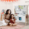 Wooden pretend play kitchen set for toddlers in white, featuring a microwave, sink, and cooking accessories for.