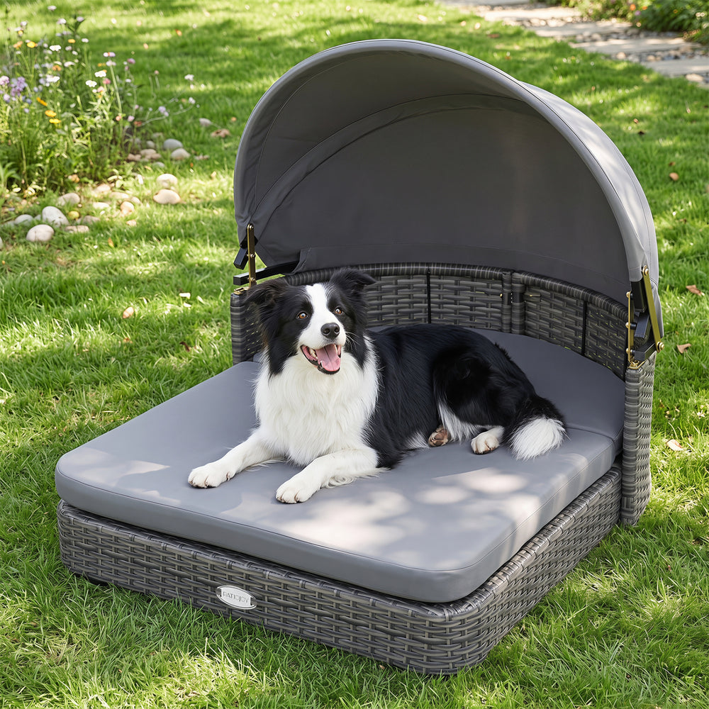 Wicker dog house with adjustable canopy and gray cushions, designed for small to medium dogs, offers cozy outdoor lounging.