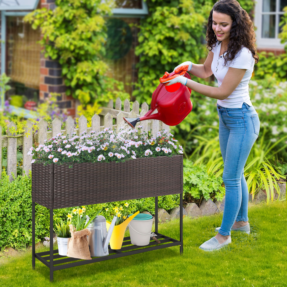 Wicker raised garden bed with storage shelf, featuring drainage gaps, ideal for growing flowers and herbs in the garden.