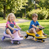 Two children riding the Wiggle Car Ride-on Toy with flashing wheels, one in yellow and one in purple, outdoors.