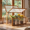 Wood cold frame greenhouse with transparent openable roof, featuring sunflowers and plants for indoor gardening.