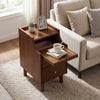 Wood nightstand with drawers and solid wood legs in brown, featuring an open shelf and a cozy living room setting.