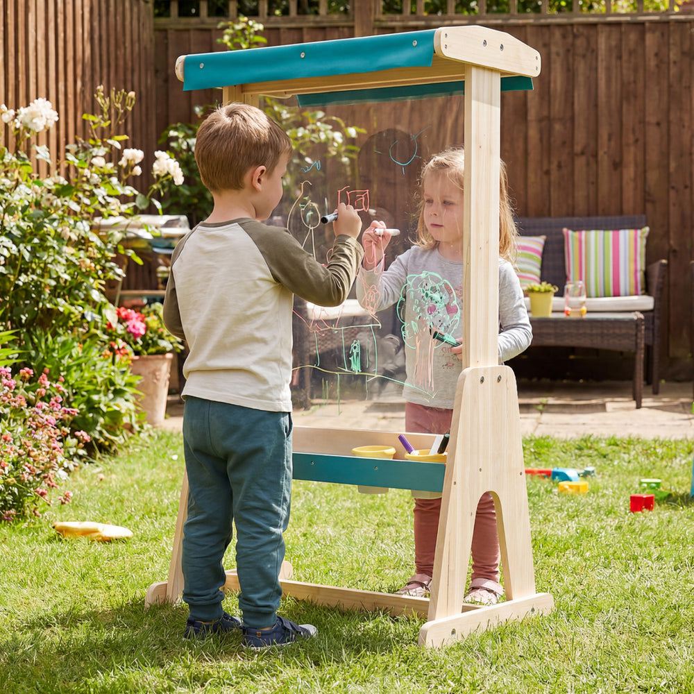 Kids using a wooden art easel with a transparent board and paper roll for creative outdoor painting activities.