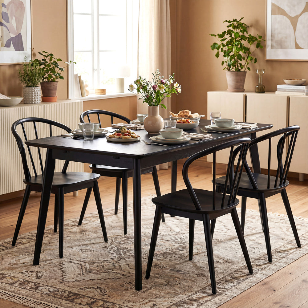 Black wooden dining chair set with high spindle backs and wide seats, perfect for dining rooms and cafes.
