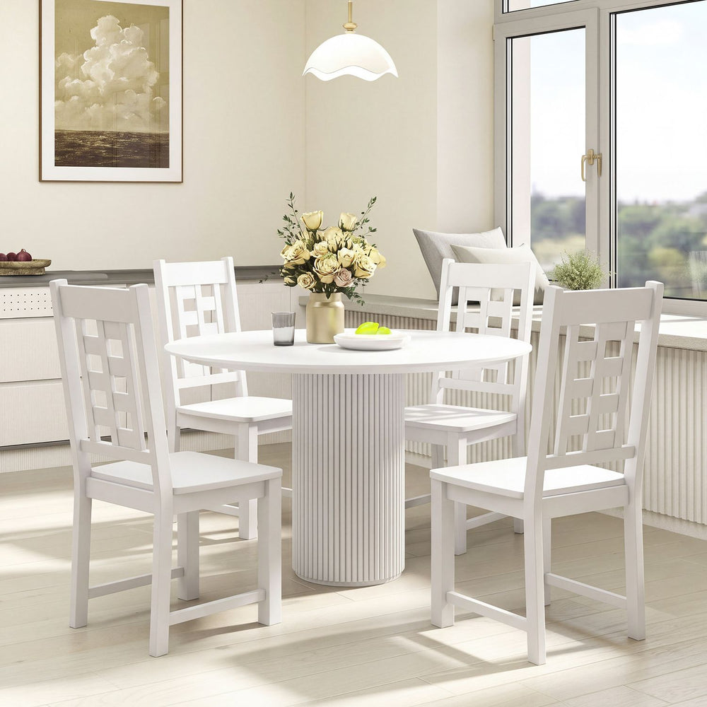 Round white dining table with four matching chairs, showcasing a solid rubber wood frame and elegant design for versatile spaces.