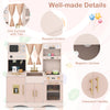 Wooden kids pretend play toy kitchen in pink features a microwave, coffee maker, and rounded corners for safe play.
