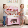Wooden play kitchen in pink with accessories, featuring a clock, for kids' pretend play and imaginative learning.