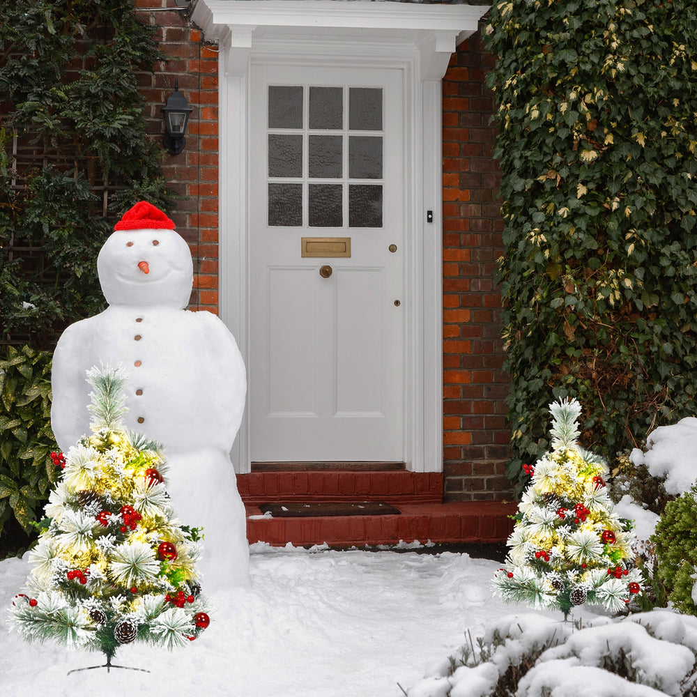 Pre-lit 2 feet flocked Christmas trees with red balls and warm LED lights, perfect for festive outdoor decoration.