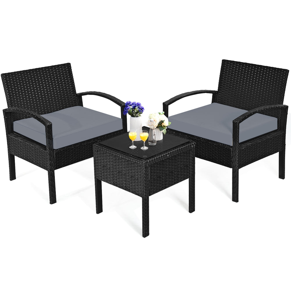 Three-piece outdoor rattan patio conversation set with gray cushions, featuring a tempered glass table for stylish.