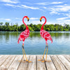 Two pink flamingo garden statues made of rustproof metal, perfect for charming backyard or lakeside decoration.