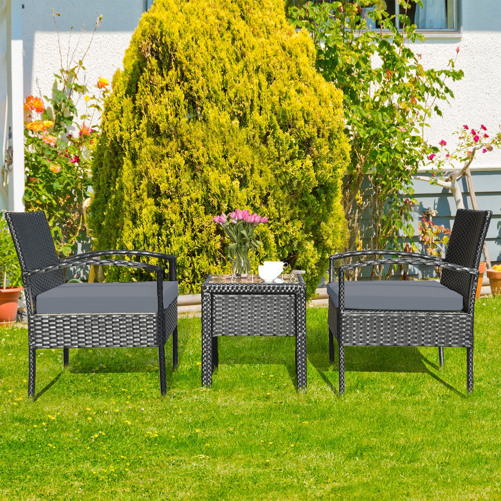 Rattan patio conversation set with gray cushions, featuring a table and two chairs, perfect for outdoor relaxation.