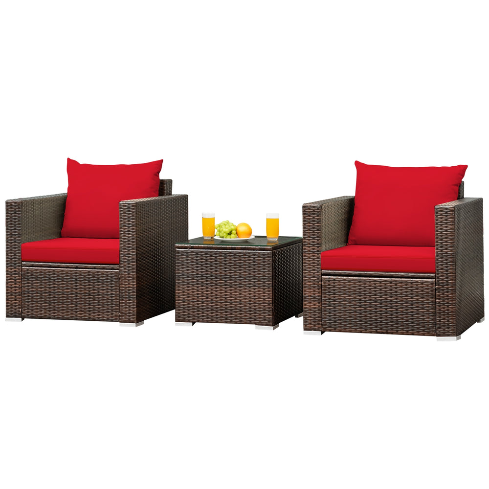 Two red-cushioned patio chairs and a glass-top table, made of durable rattan, perfect for outdoor relaxation.