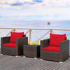 Two red-cushioned rattan chairs with a glass-top table, perfect for outdoor patio relaxation.