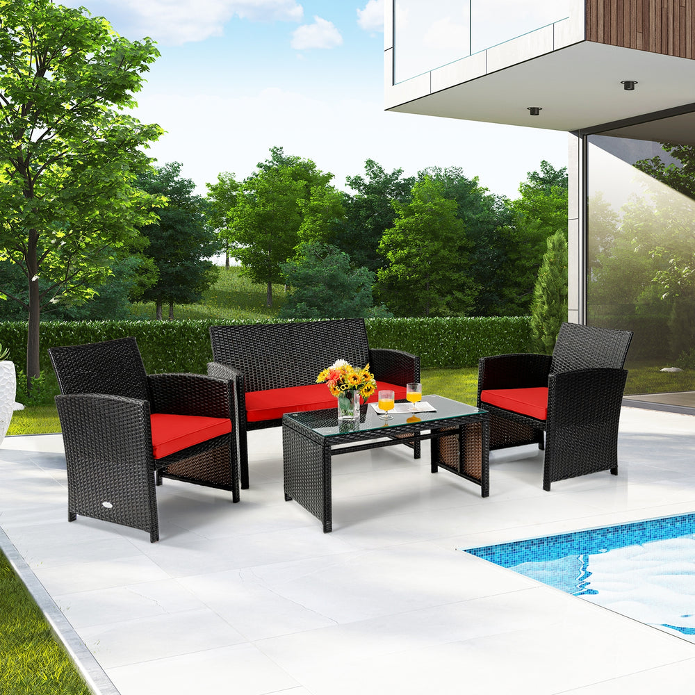 Four-piece patio rattan furniture set with red cushions, including loveseat, chairs, and tempered glass coffee table.