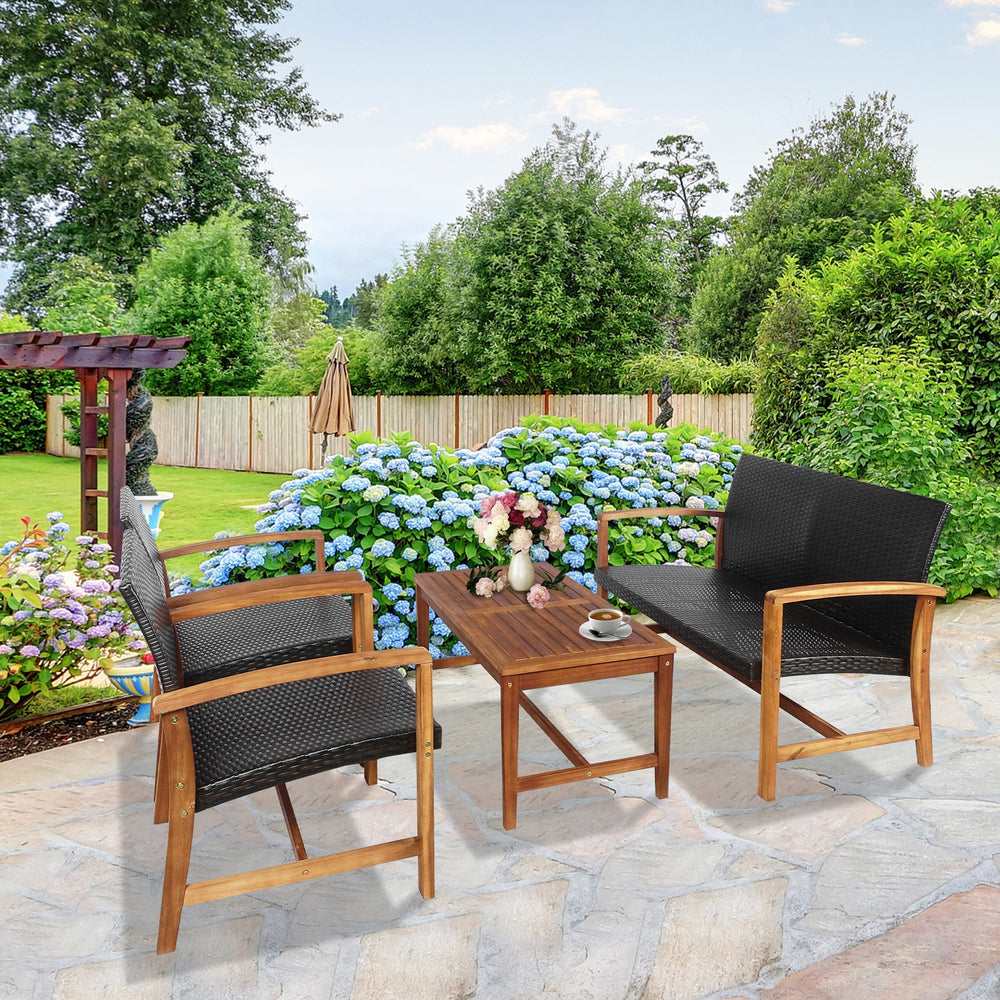 Two chairs and a coffee table from a 4-piece PE rattan patio furniture set with solid acacia wood, ideal for outdoor.