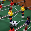 Foosball players in yellow and red on a green tabletop, part of a 2-in-1 indoor/outdoor game table.