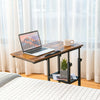 Adjustable C-shaped bedside table in rustic brown with a laptop, featuring a 2-tier shelf and lockable wheels for.