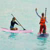 Two paddlers on inflatable stand-up paddle boards in clear water, showcasing stability and ease of use for all skill.