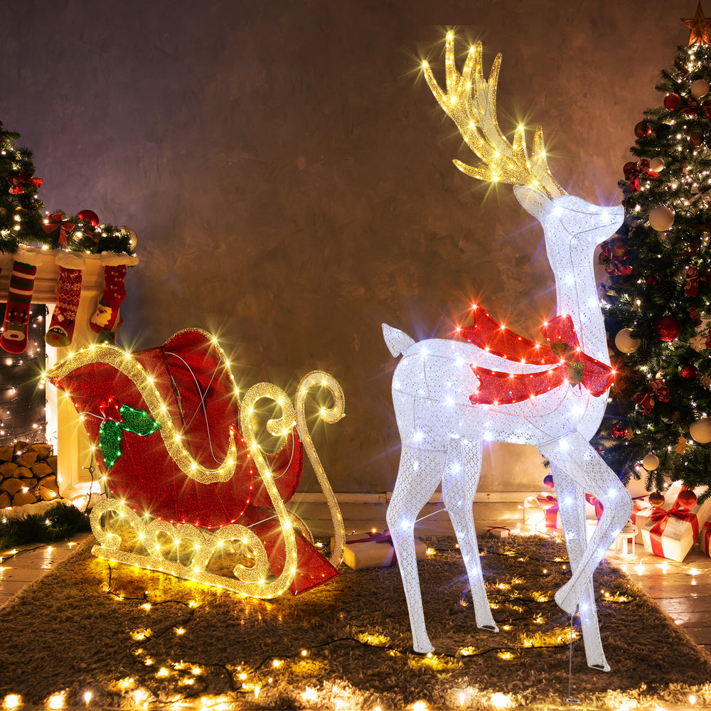 LED lighted Christmas reindeer with antlers and bow beside Santa's sleigh, perfect for festive indoor and outdoor.