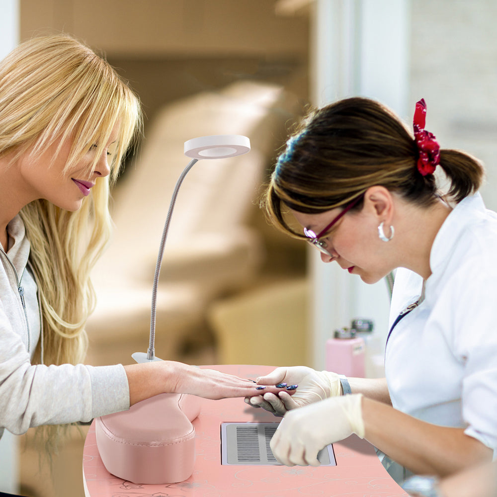 Manicure nail table in pink with a bendable USB LED lamp, featuring a dust collector and soft wrist pad for comfort.